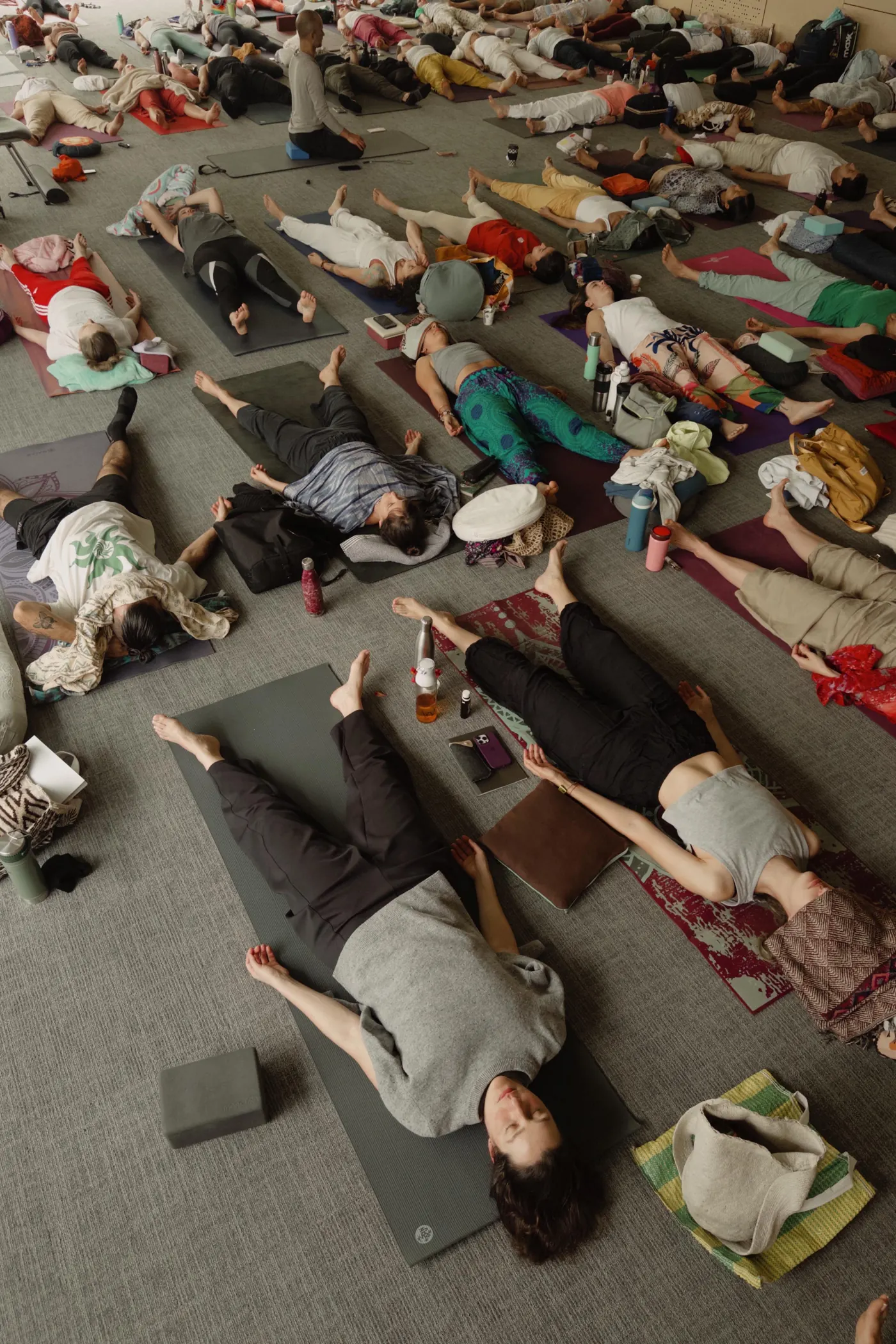 Un grupo de personas acostadas en el suelo, con los ojos cerrados, durante una práctica de Prana Nidra